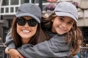 Deborah Secco e Maria Flor de casaco e boné cinza sorrindo
