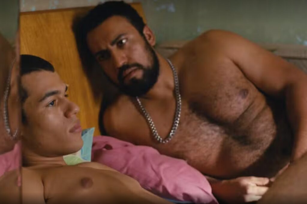 Ricardo Teodoro deitado na cama, sem camisa, no filme "Baby" 