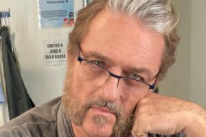 Werner Schünemann com a mão no queixo, de óculos e roupão