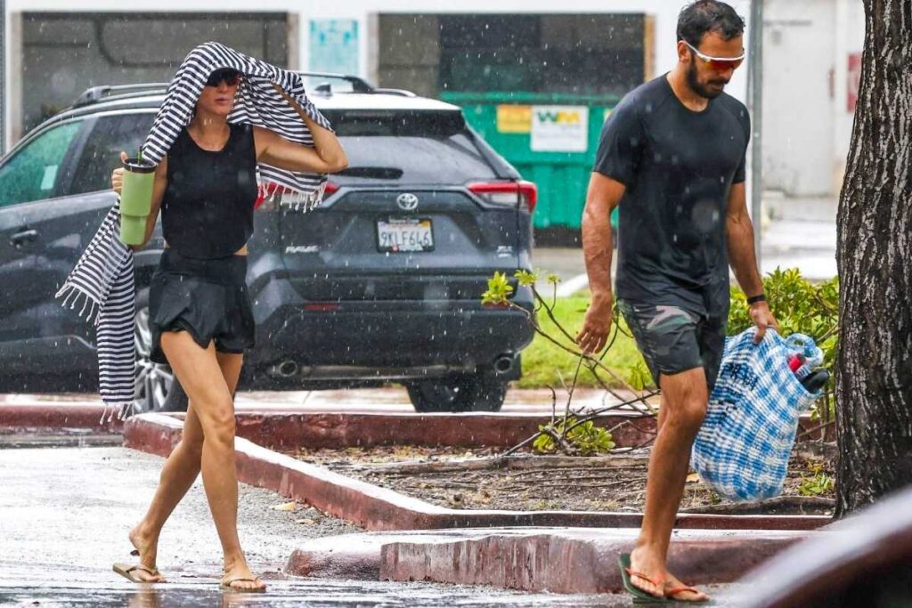 Gisele Bündchen e Joaquim Valente tomando chuva em beach tênis