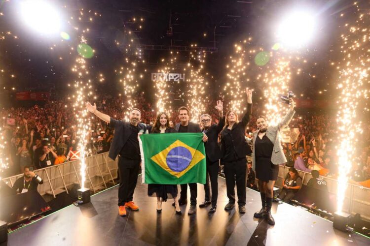 Elenco de de "Bailarina" com bandeira do Brasil em painel na CCXP24