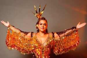 preta gil com roupas de carnaval e de braços abertos