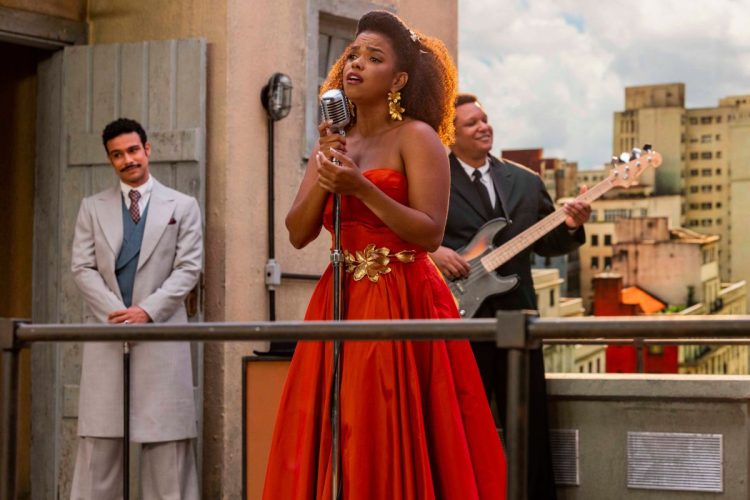 Dita (Jeniffer Nascimento) chega no terraço para cantar em Êta Mundo Melhor